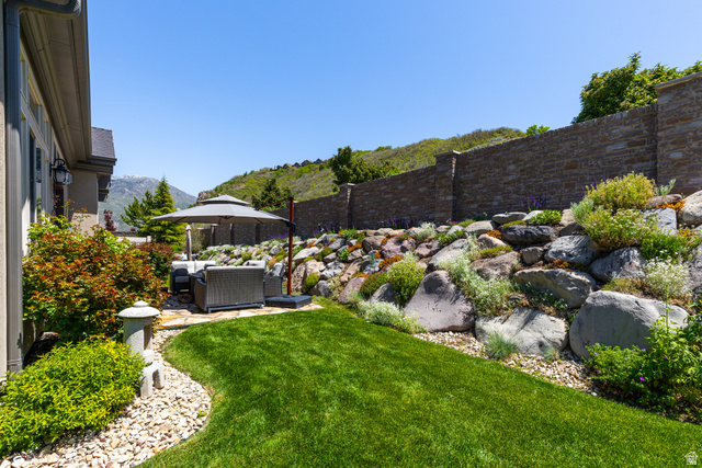 1132 Sunset Dunes Way Draper, UT 84020 - Photo 29 of 35 Expansive backyard featuring a manicured lawn, stone patio, and a terraced rock garden with diverse plantings