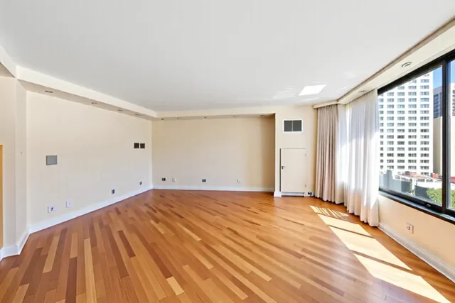 a view of empty room with wooden floor and fan