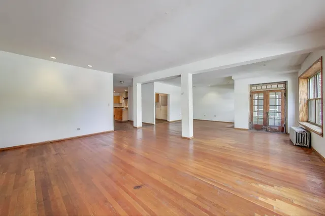 a view of an empty room with window and wooden floor