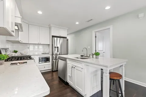 a kitchen with a sink a stove a refrigerator and white cabinets