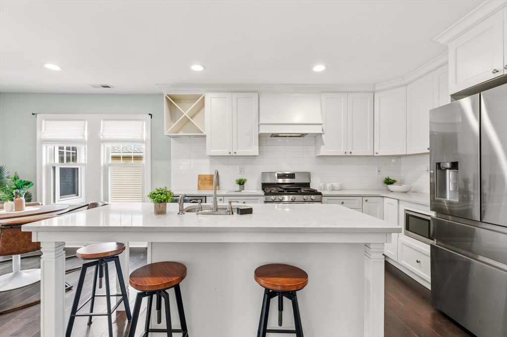 63 Century Street, Unit 2 Medford, MA 02155 - Photo 15 of 35 a kitchen with stainless steel appliances granite countertop a sink a stove a refrigerator and white cabinets with wooden floor