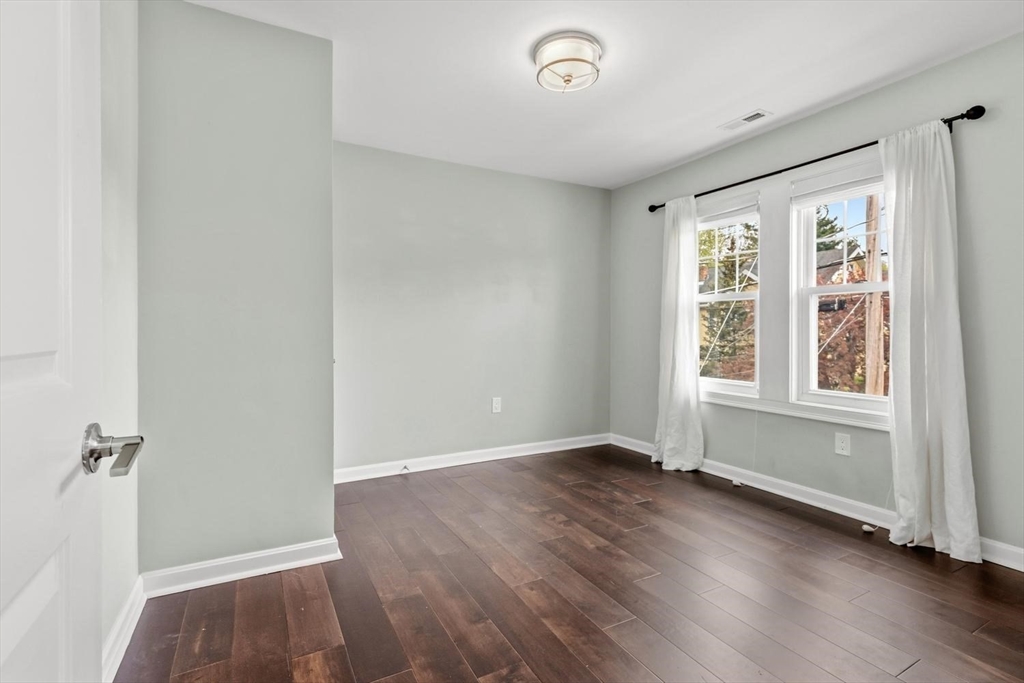 63 Century Street, Unit 2 Medford, MA 02155 - Photo 20 of 35 an empty room with wooden floor and windows