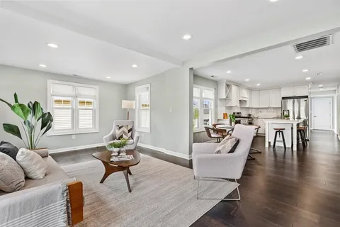 a living room with furniture and a dining table with wooden floor