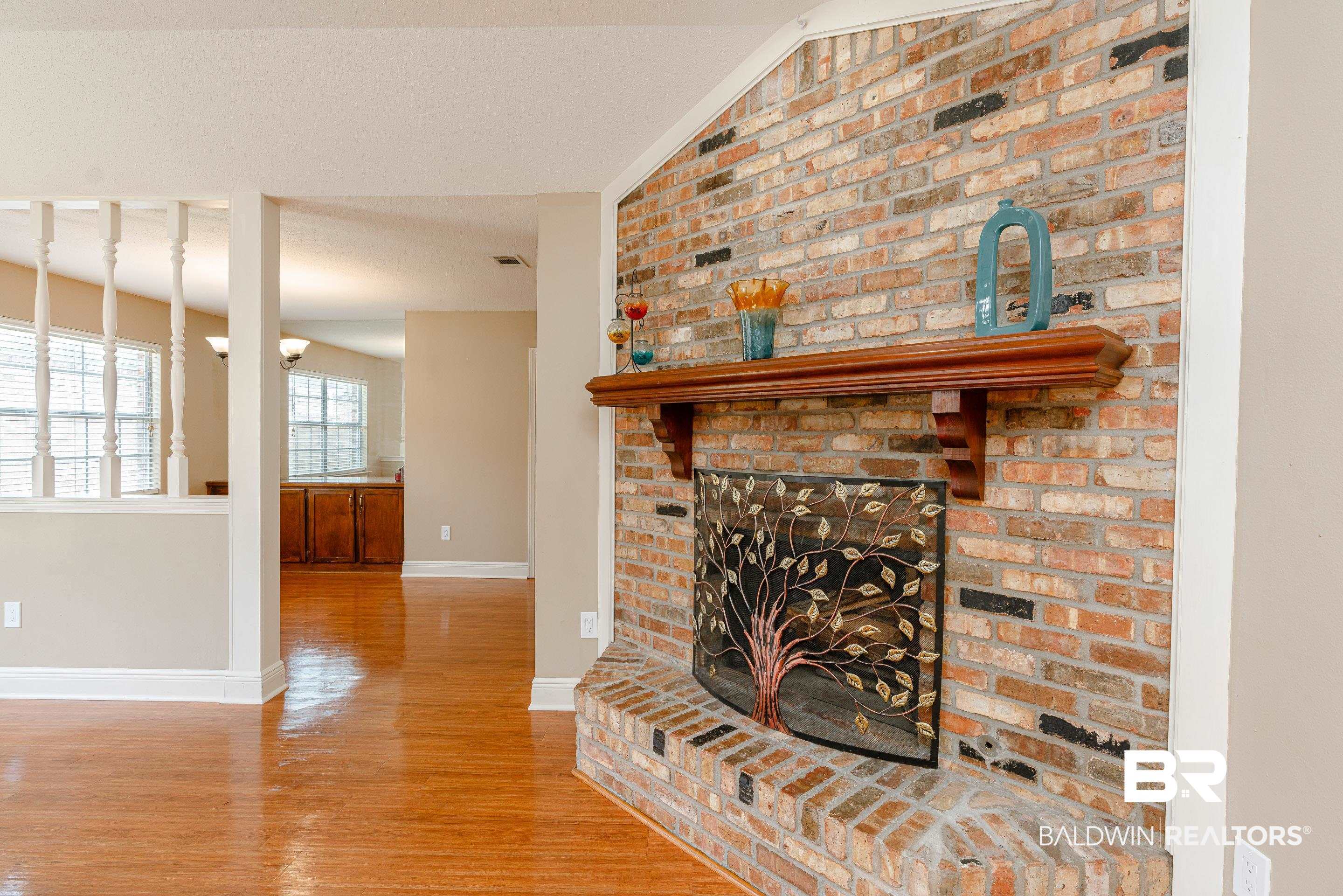 23 Old Mill Court Mobile, AL 36608 - Photo 8 of 37 Living room with lofted ceiling, a brick fireplace, brick wall, and light wood-type flooring