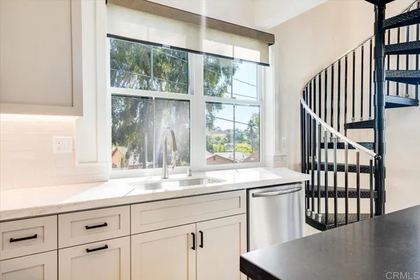 a kitchen with granite countertop a window a sink and white cabinets