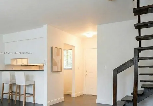 an empty room with wooden floor cabinet and windows