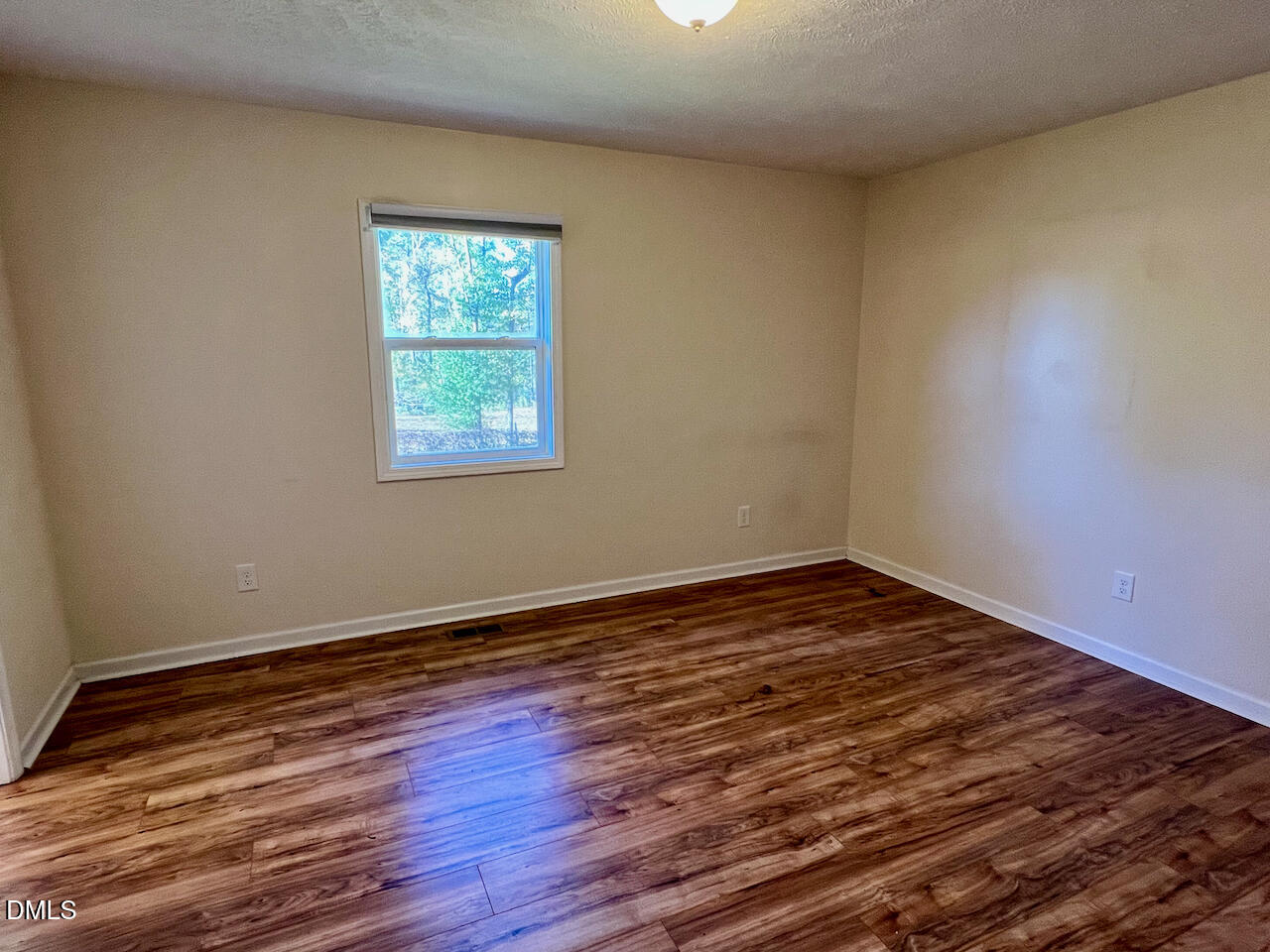 1421 Creech Road Garner, NC 27529 - Photo 8 of 22 a view of an empty room with wooden floor and a window