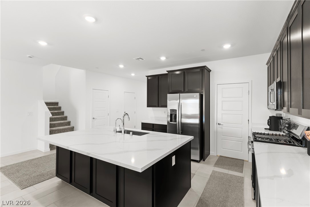 320 Isla Enclave Way Henderson, NV 89011 - Photo 2 of 49 A well-appointed kitchen showcasing a spacious central island with a sink and ample counter space, alongside modern stainless steel appliances.