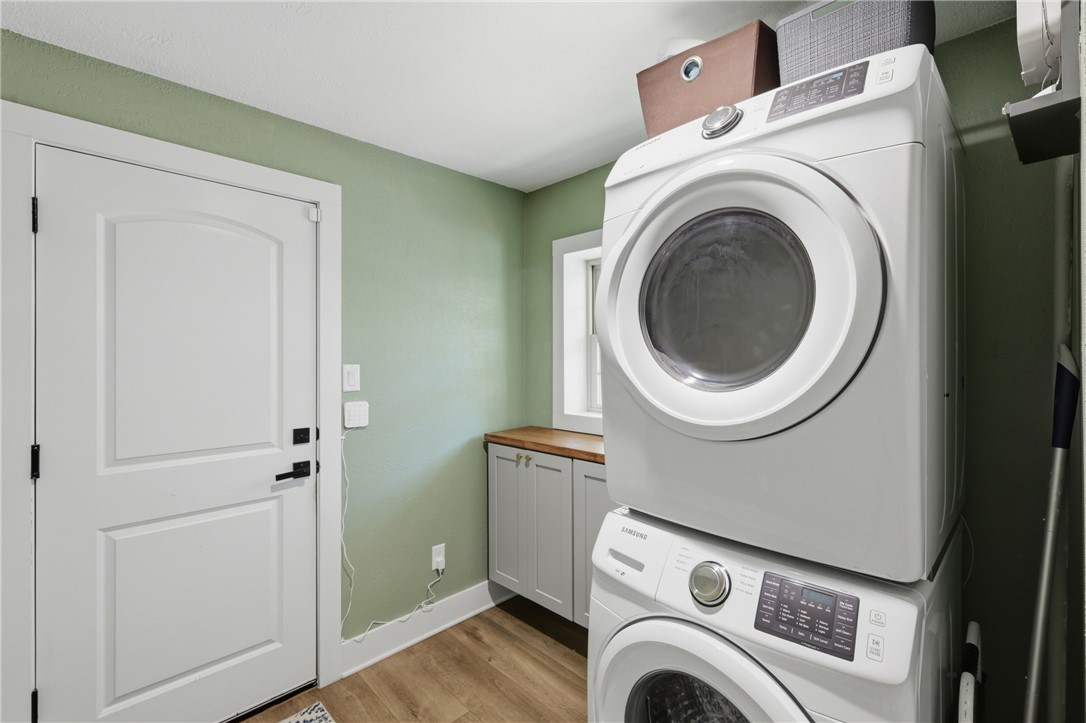 515 Crescent Drive Bryan, TX 77801 - Photo 31 of 43 Dedicated laundry area featuring stacked appliances, wood-look LVP flooring, a white paneled door, and cabinetry with a wood countertop