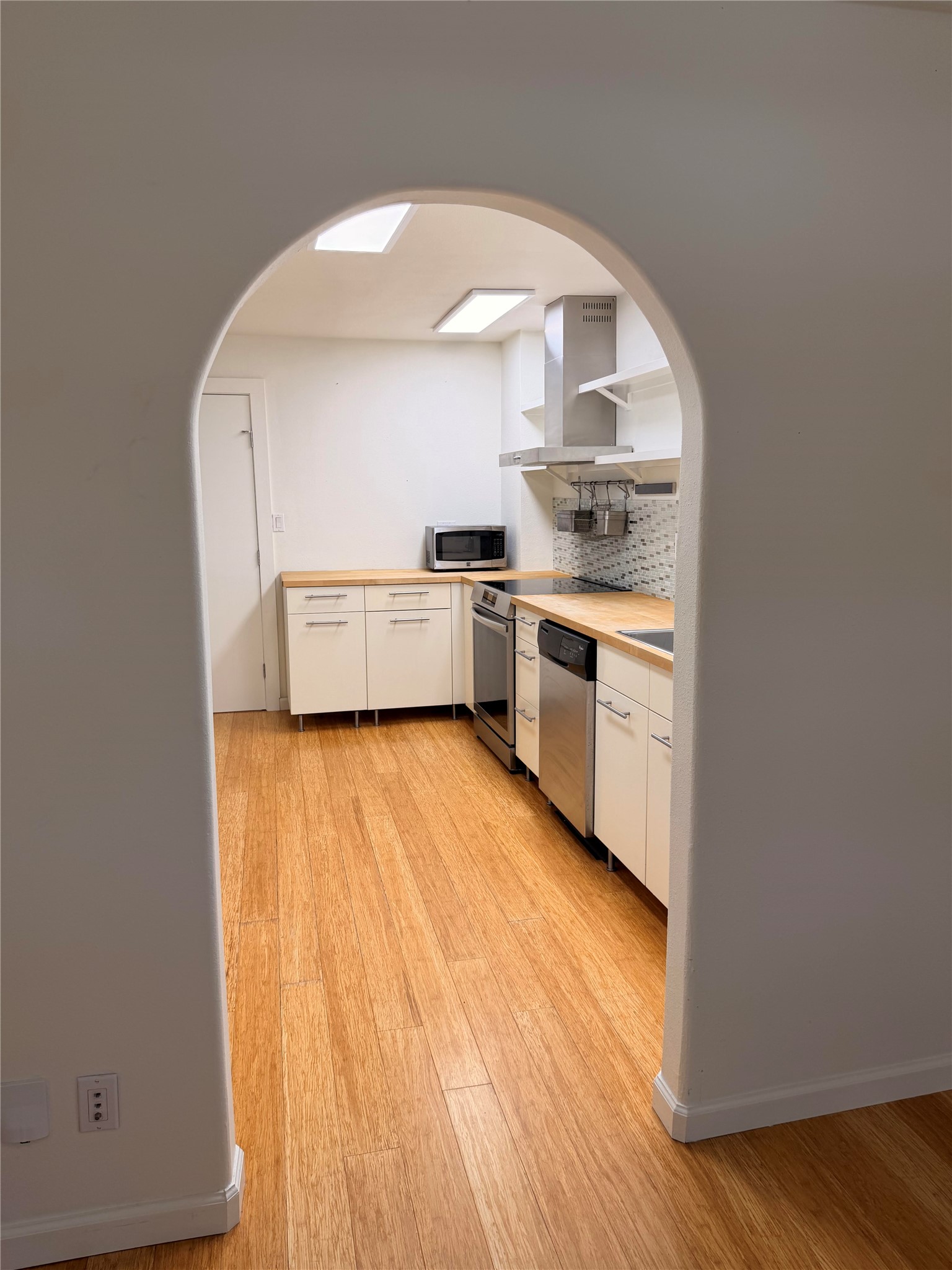1182 Pandora Street Austin, TX 78702 - Photo 3 of 19 Natural wood flooring complements this galley kitchen, equipped with stainless steel appliances and abundant counter space.