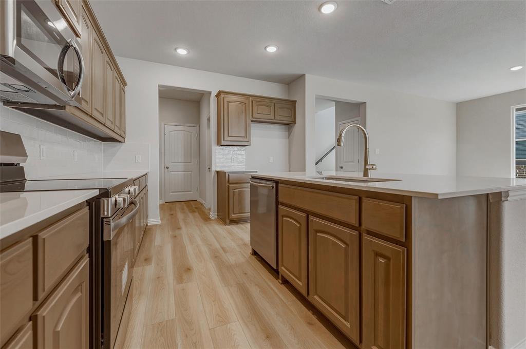 1337 Frio Drive Springtown, TX 76082 - Photo 13 of 40 Kitchen featuring wood-finish cabinetry, stainless steel appliances, white countertops, and a large island with an integrated sink