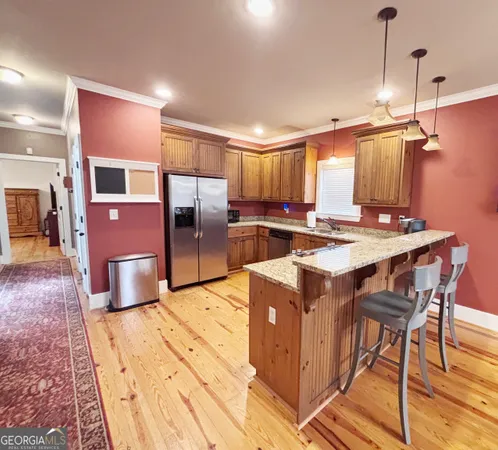 a kitchen with stainless steel appliances granite countertop a stove top oven a sink dishwasher and a refrigerator with wooden floor