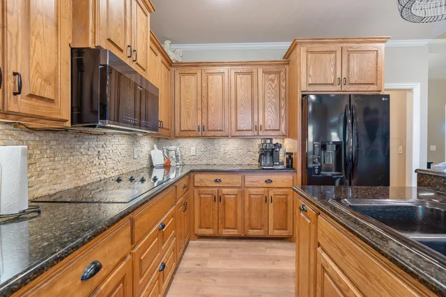 a kitchen with stainless steel appliances granite countertop a sink a stove and a wooden floors
