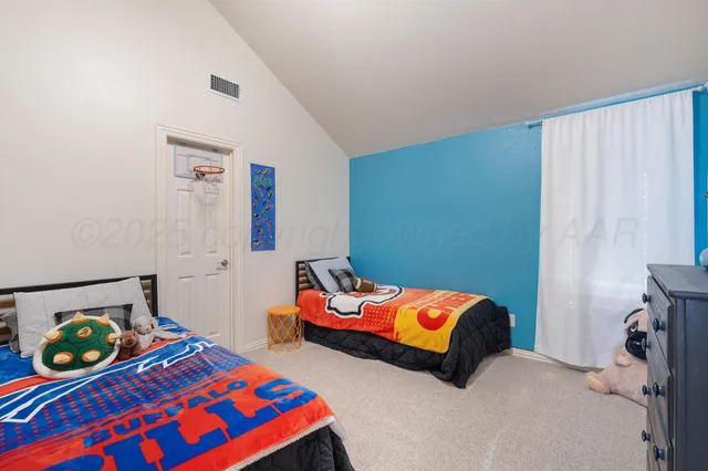 a bedroom with a bed a dresser and a chandelier