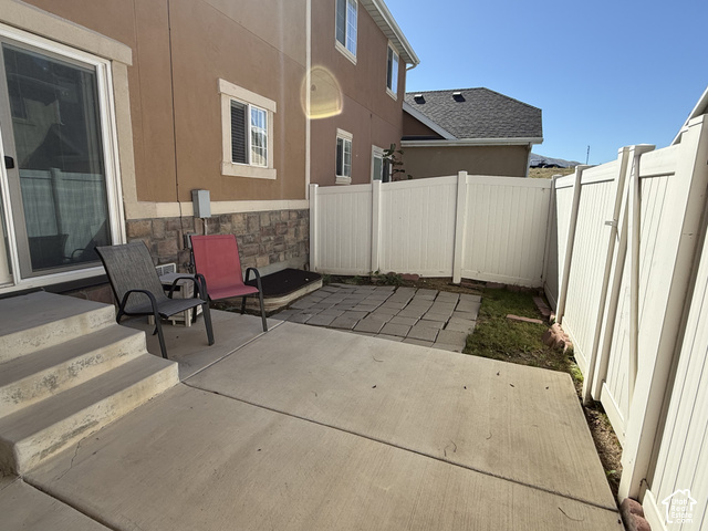 13548 South Villa Rosa Way Draper, UT 84020 - Photo 23 of 28 Concrete patio with steps, vinyl privacy fencing, and stone veneer foundation detailing