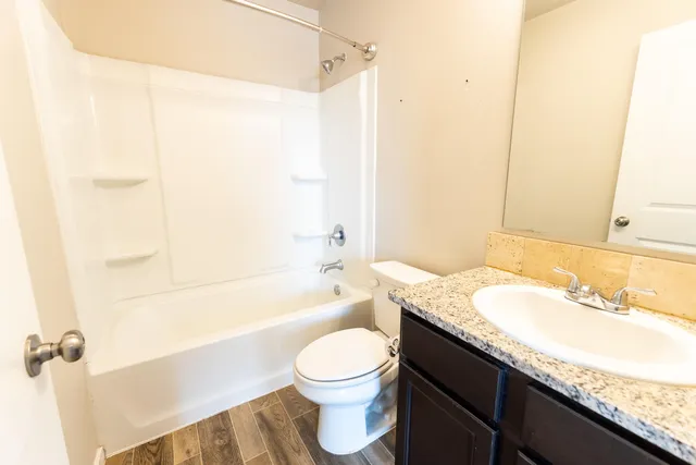 a bathroom with a granite countertop sink a toilet and shower