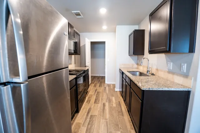 a kitchen with granite countertop a refrigerator a sink and dishwasher with wooden floor