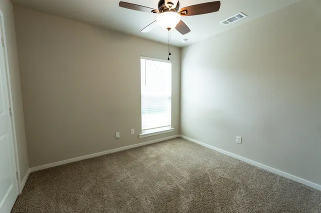 an empty room with a window and a fan