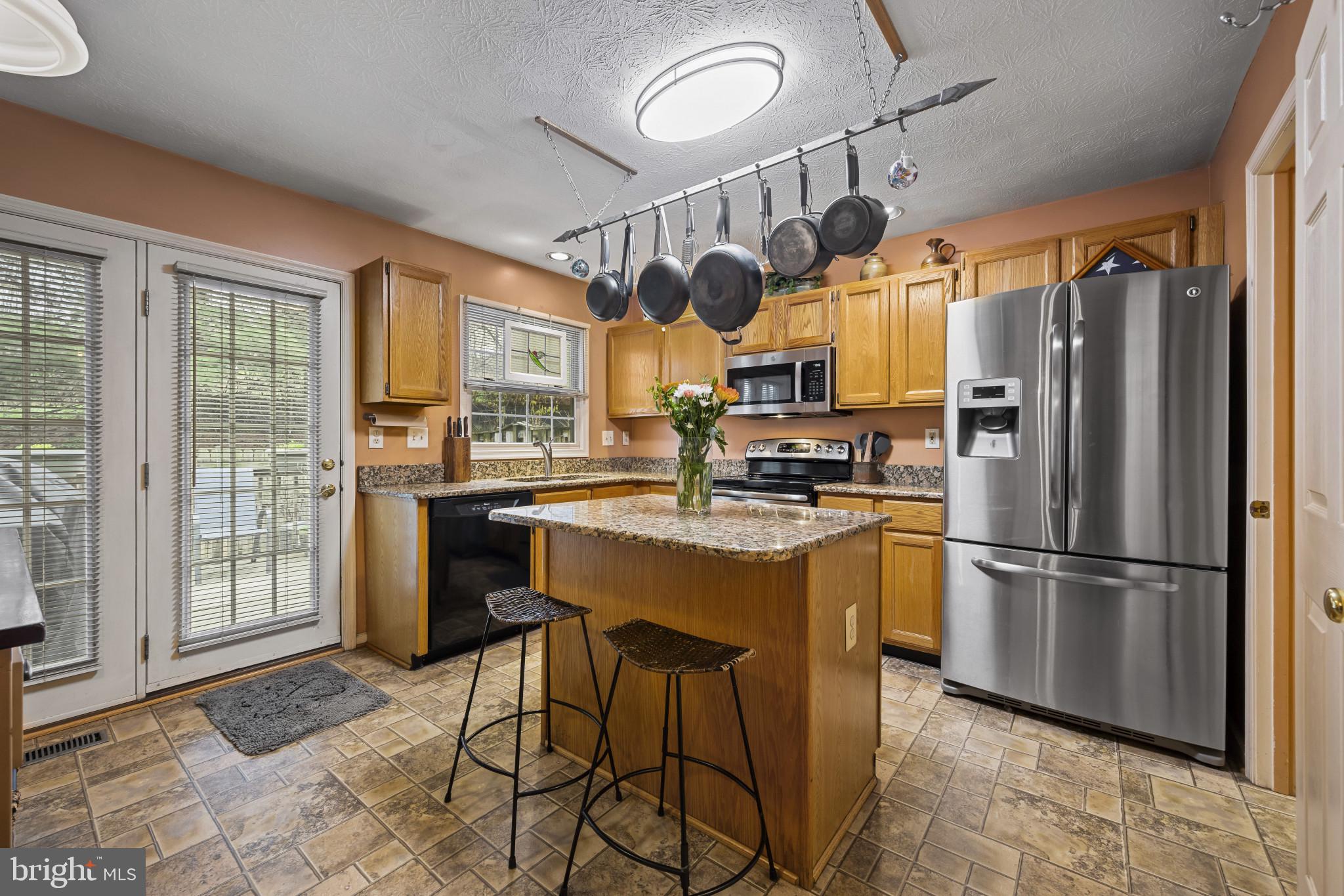 5 Wincrest Court Baltimore, MD 21208 - Photo 10 of 30 a kitchen with stainless steel appliances granite countertop a refrigerator a sink dishwasher a dining table and chairs with wooden floor