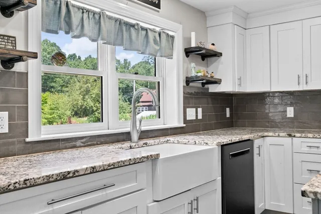 a kitchen with granite countertop stainless steel appliances white cabinets and a window
