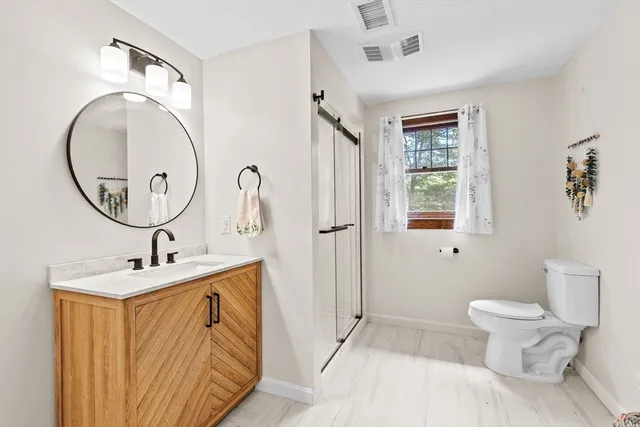 a bathroom with a sink a mirror a toilet and a shower