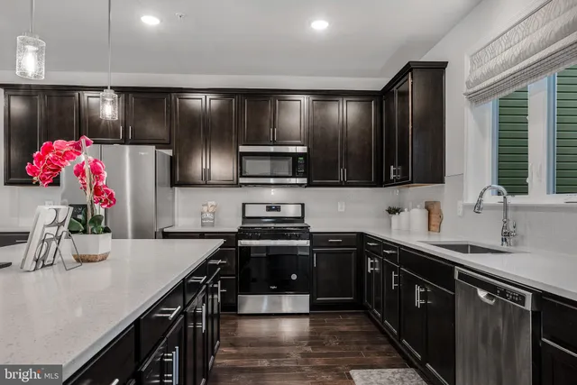 a kitchen with stainless steel appliances a sink wooden cabinets stove top oven and microwave