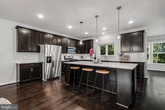 a kitchen with stainless steel appliances a refrigerator a stove a sink dishwasher a oven with white cabinets and wooden floor