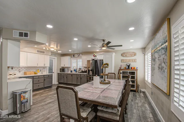 a open dining room with stainless steel appliances kitchen island granite countertop a table chairs and a refrigerator