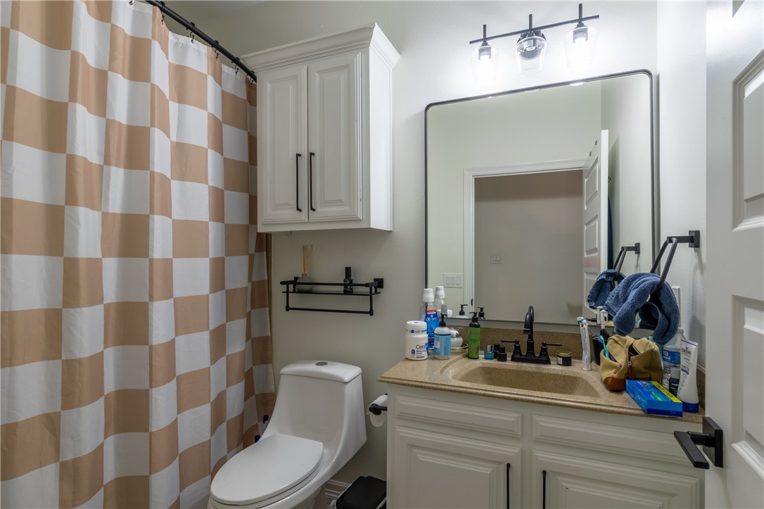 108 County Road 1601 Alice, TX 78332 - Photo 25 of 32 a bathroom with a sink a toilet a mirror and shower curtain