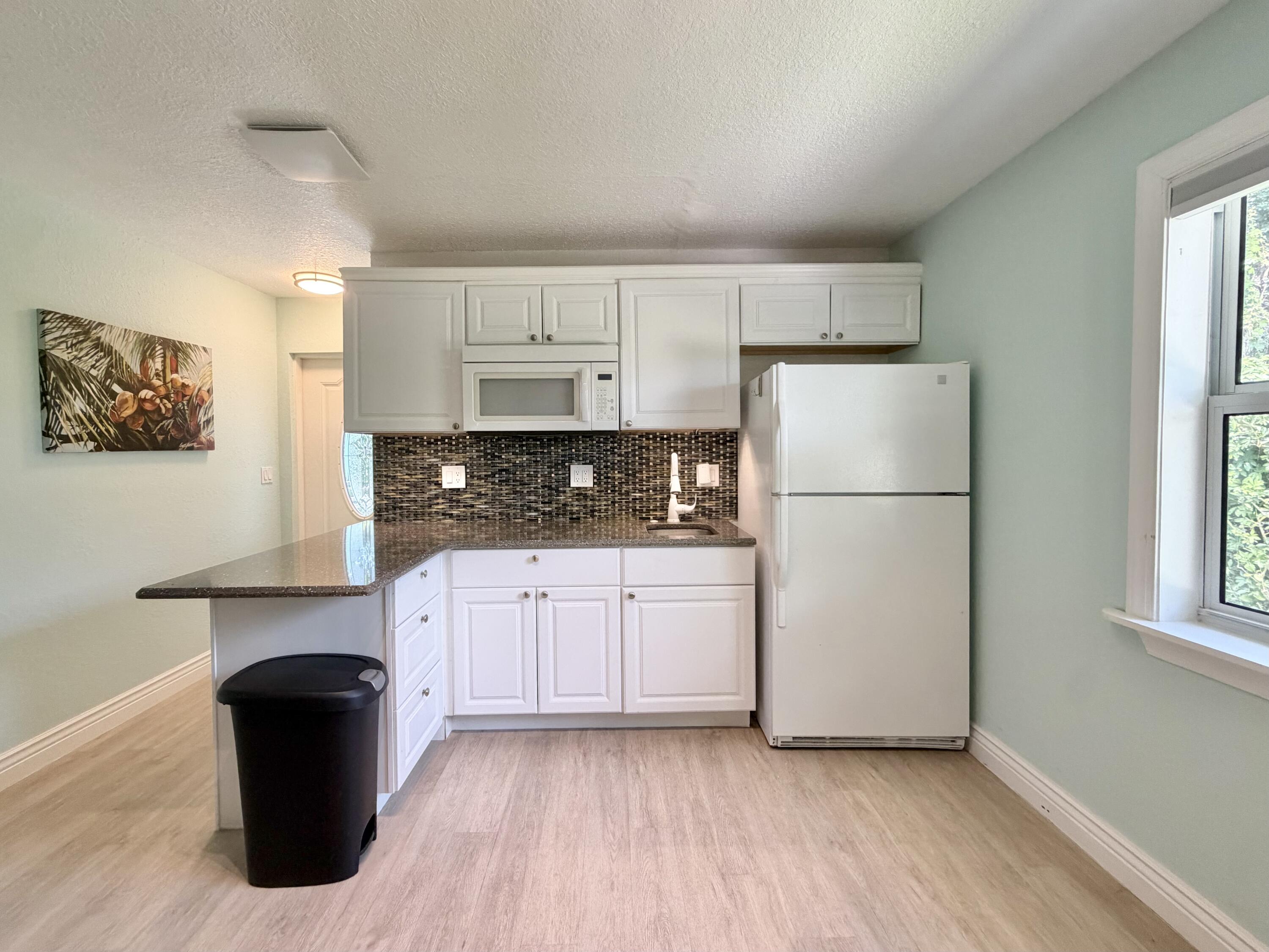 6100 Francis Street, Unit B Jupiter, FL 33458 - Photo 4 of 19 a kitchen with a refrigerator and white cabinets