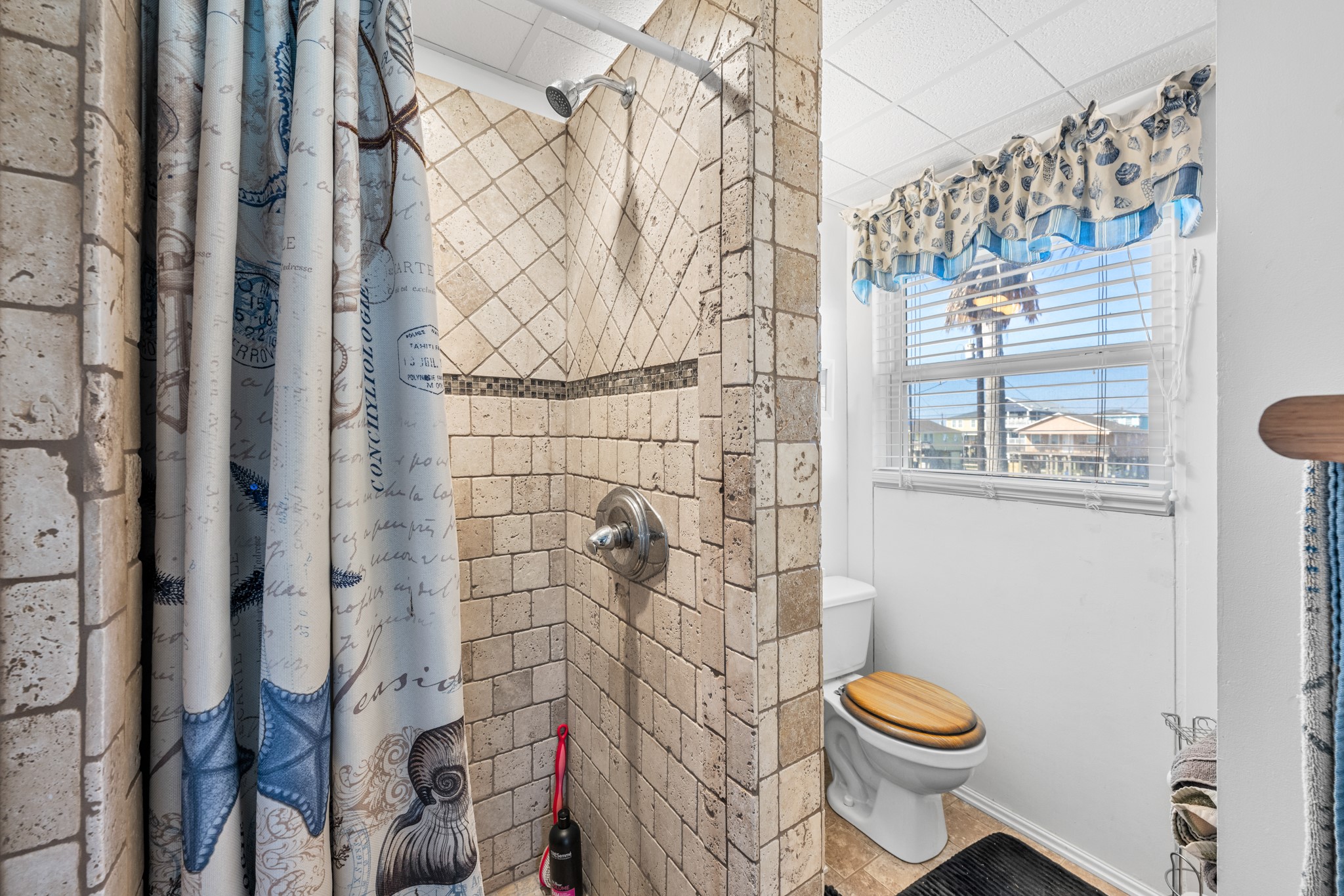 702 Seashell Drive Surfside Beach, TX 77541 - Photo 20 of 40 Updated bathroom with a tiled walk-in shower, coordinating tile accents, and a window providing natural light and coastal views.