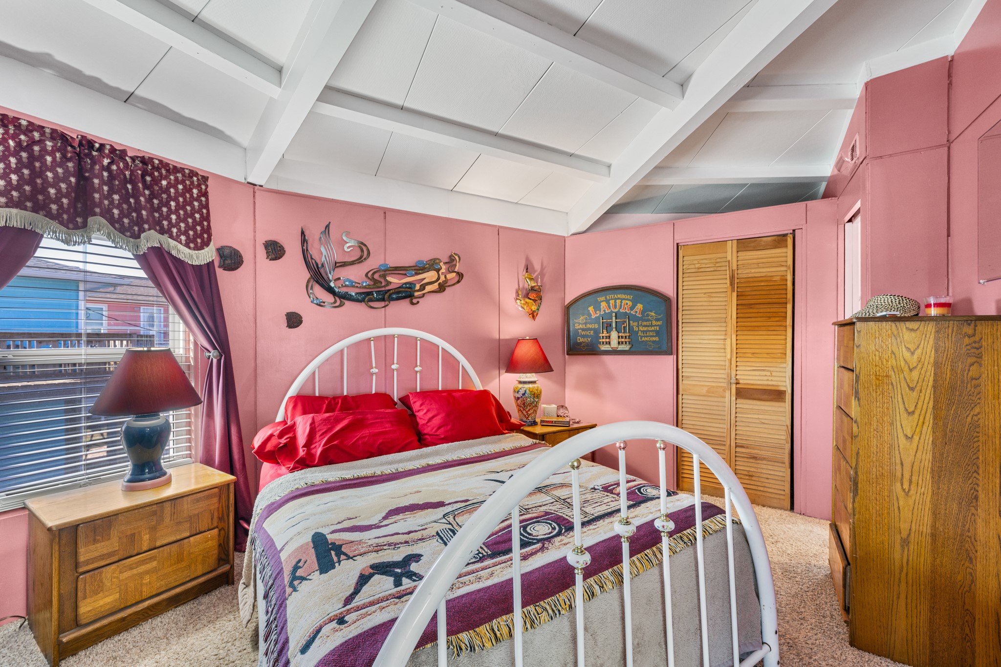 702 Seashell Drive Surfside Beach, TX 77541 - Photo 22 of 40 Cozy guest room with warm coral tones, decorative wall art, and natural light that enhances the space’s welcoming feel.