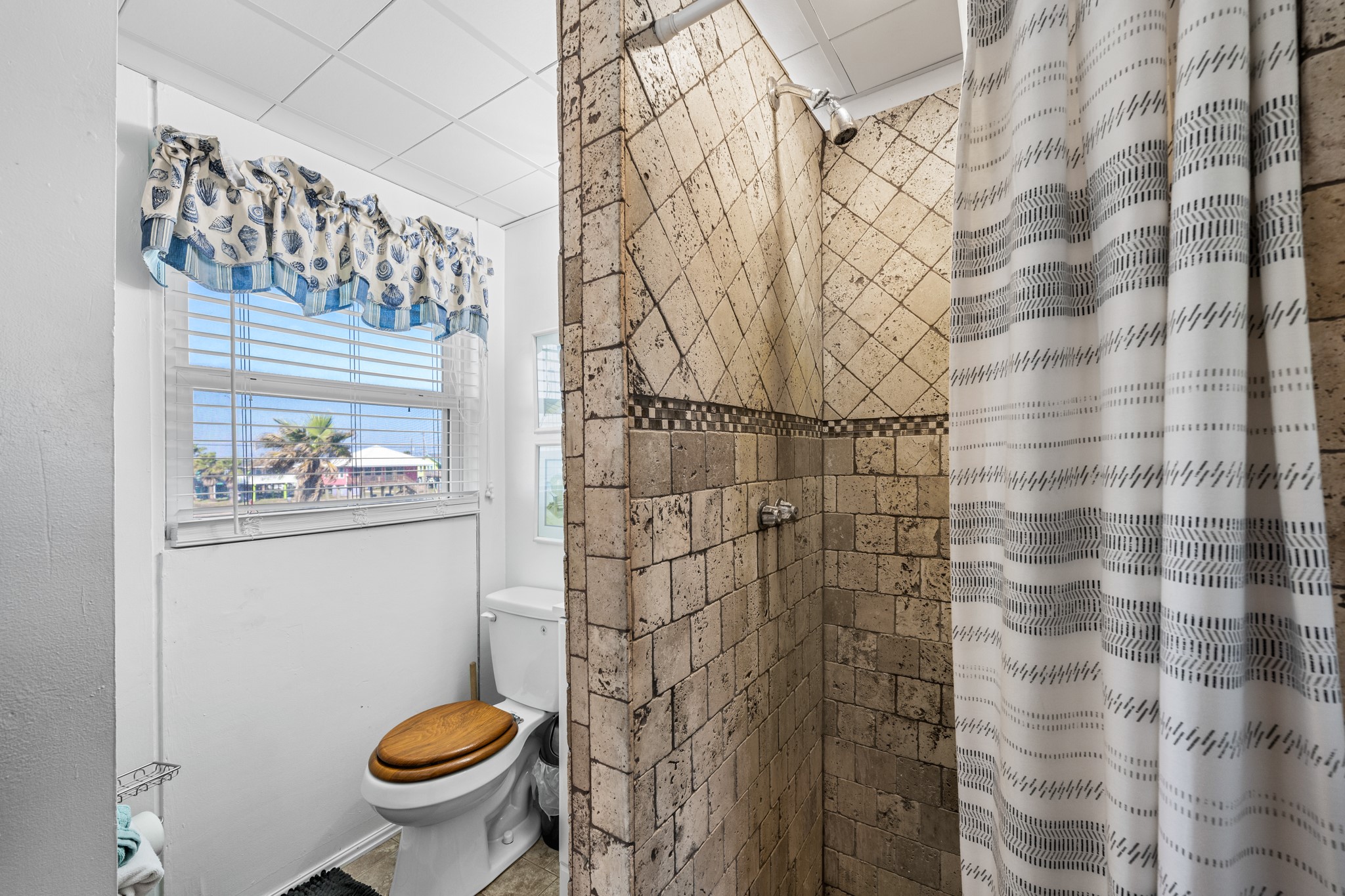 702 Seashell Drive Surfside Beach, TX 77541 - Photo 27 of 40 Additional full bath featuring tiled shower surround, seashell-inspired window treatments, and a bright, cheerful atmosphere.