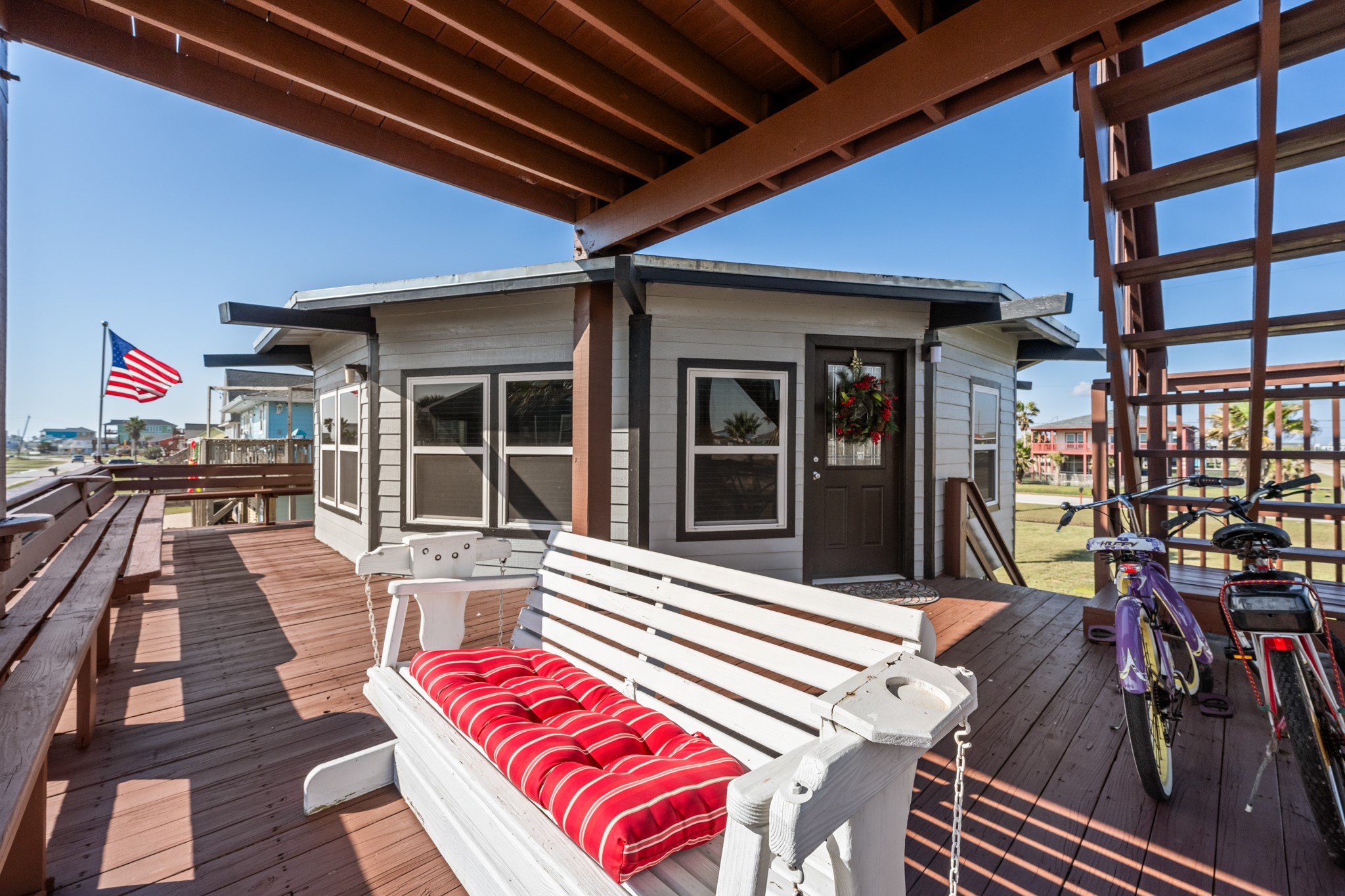 702 Seashell Drive Surfside Beach, TX 77541 - Photo 31 of 40 Spacious wraparound deck offers ample seating, including a porch swing, and easy access to the elevated front entrance—perfect for enjoying Gulf breezes and outdoor living.