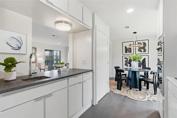 a dining hall with stainless steel appliances kitchen island granite countertop a table and chairs in it