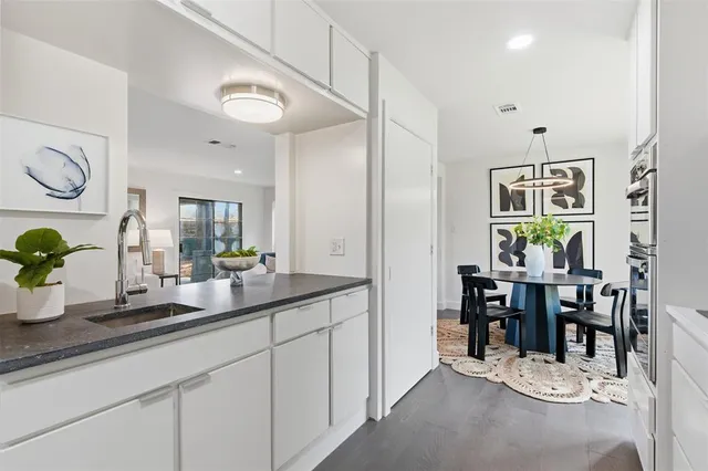 a dining hall with stainless steel appliances kitchen island granite countertop a table and chairs in it