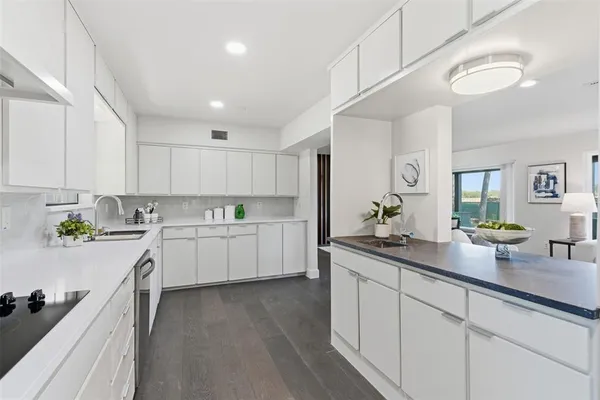 a kitchen with white cabinets and wooden floors