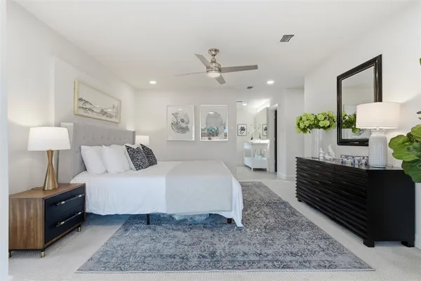 a spacious bedroom with a bed a dresser and wooden floor