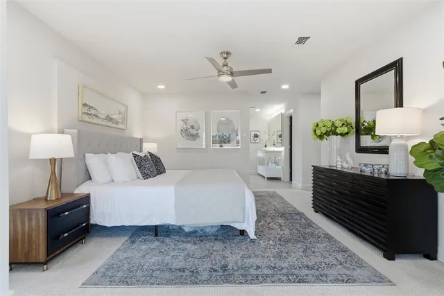 a spacious bedroom with a bed a dresser and wooden floor