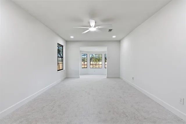 an empty room with windows and ceiling fan
