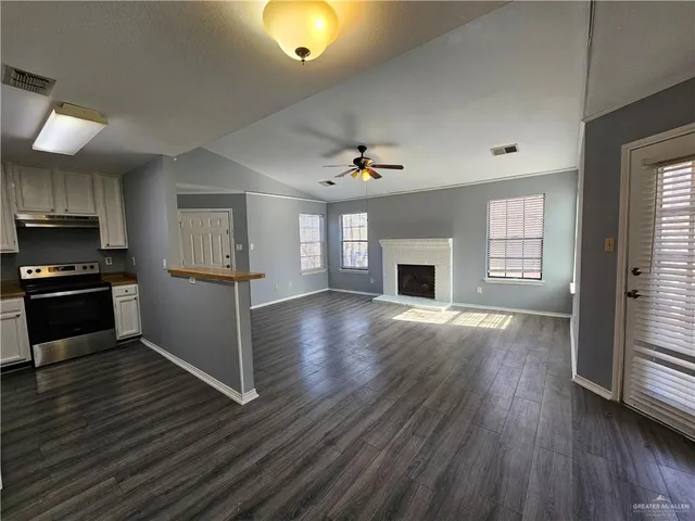 an empty room with wooden floor fireplace and windows
