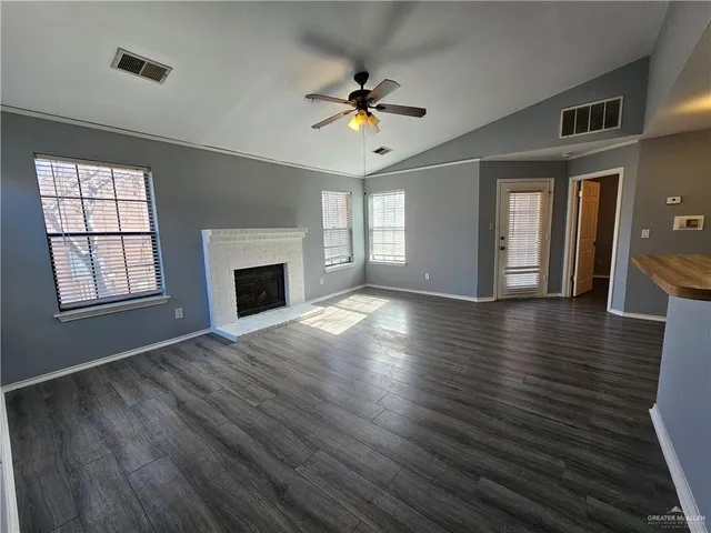 a view of a livingroom with wooden floor a ceiling fan and windows