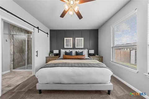 a large bed sitting in a bedroom next to a window and a chandelier