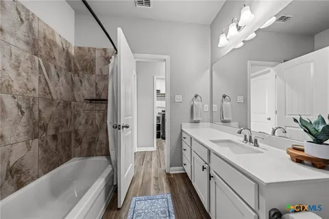 a bathroom with a double vanity sink a mirror a bathtub and a shower