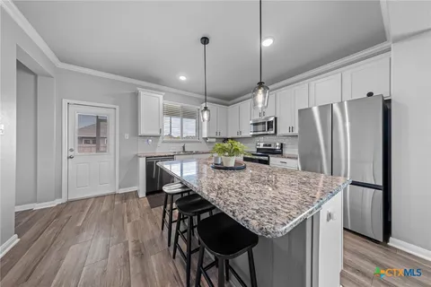 a kitchen with stainless steel appliances granite countertop a refrigerator a stove a sink dishwasher and microwave with wooden floor