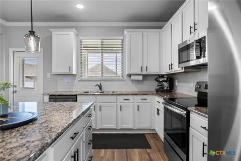 a kitchen with granite countertop a sink stove and cabinets