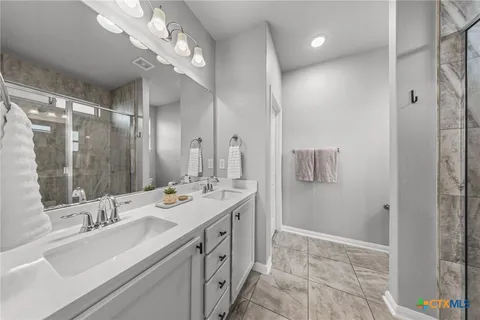 a spacious bathroom with a double vanity sink mirror and shower