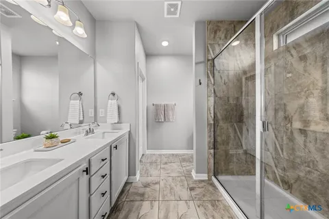a bathroom with a double vanity sink mirror and shower