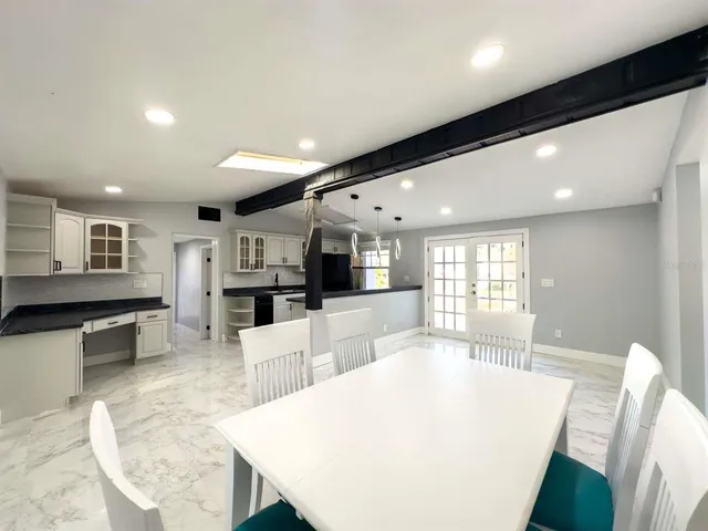 a large white kitchen with a large window a counter top space and stainless steel appliances