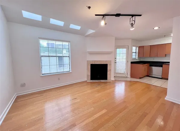 an empty room with wooden floor fireplace and windows